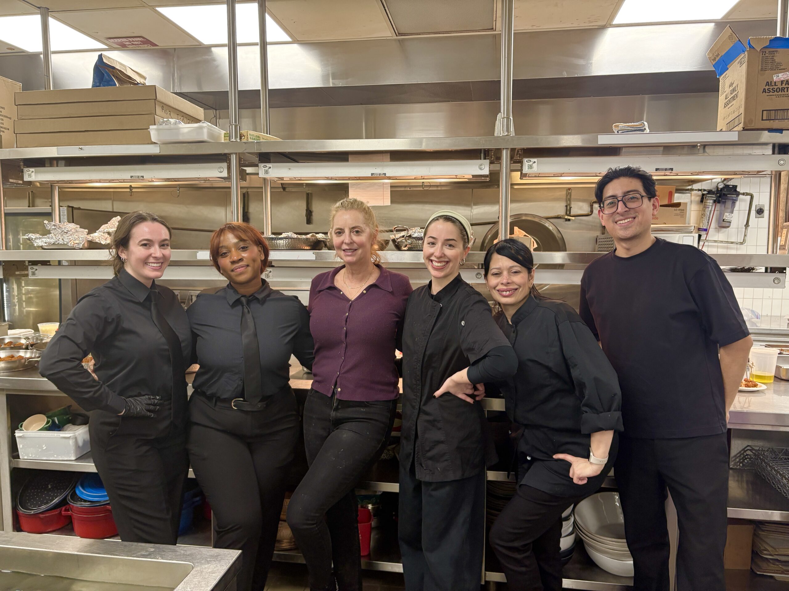 The Sweet Basil Catering team, led by founder Amy Aversa, posing together in the kitchen to showcase their teamwork and dedication.