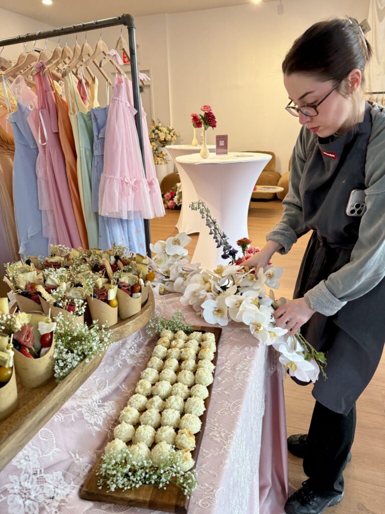 Sweet Basil team member setting up a floral catering display with savory cones and orchid accents at a New York City fashion event.