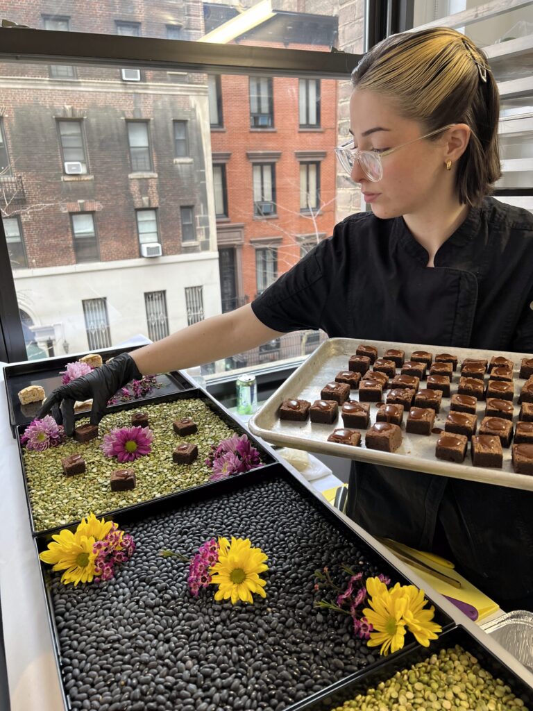 Sweet Basil chef arranging elegant chocolate bites and fresh flowers for a corporate catering display in a New York City event space.