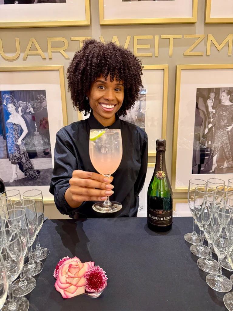 Sweet Basil bartender smiling and holding a pink cocktail at a fashion event