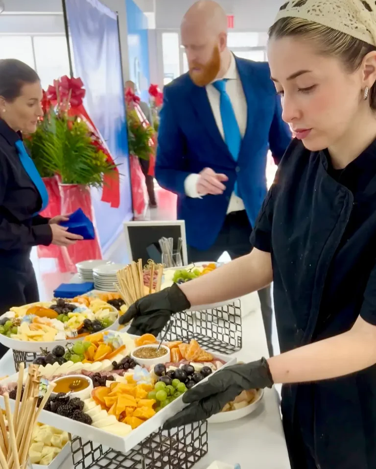 Sweet Basil staff setting up grazing platters with fresh fruit, cheeses, and dips at a corporate event