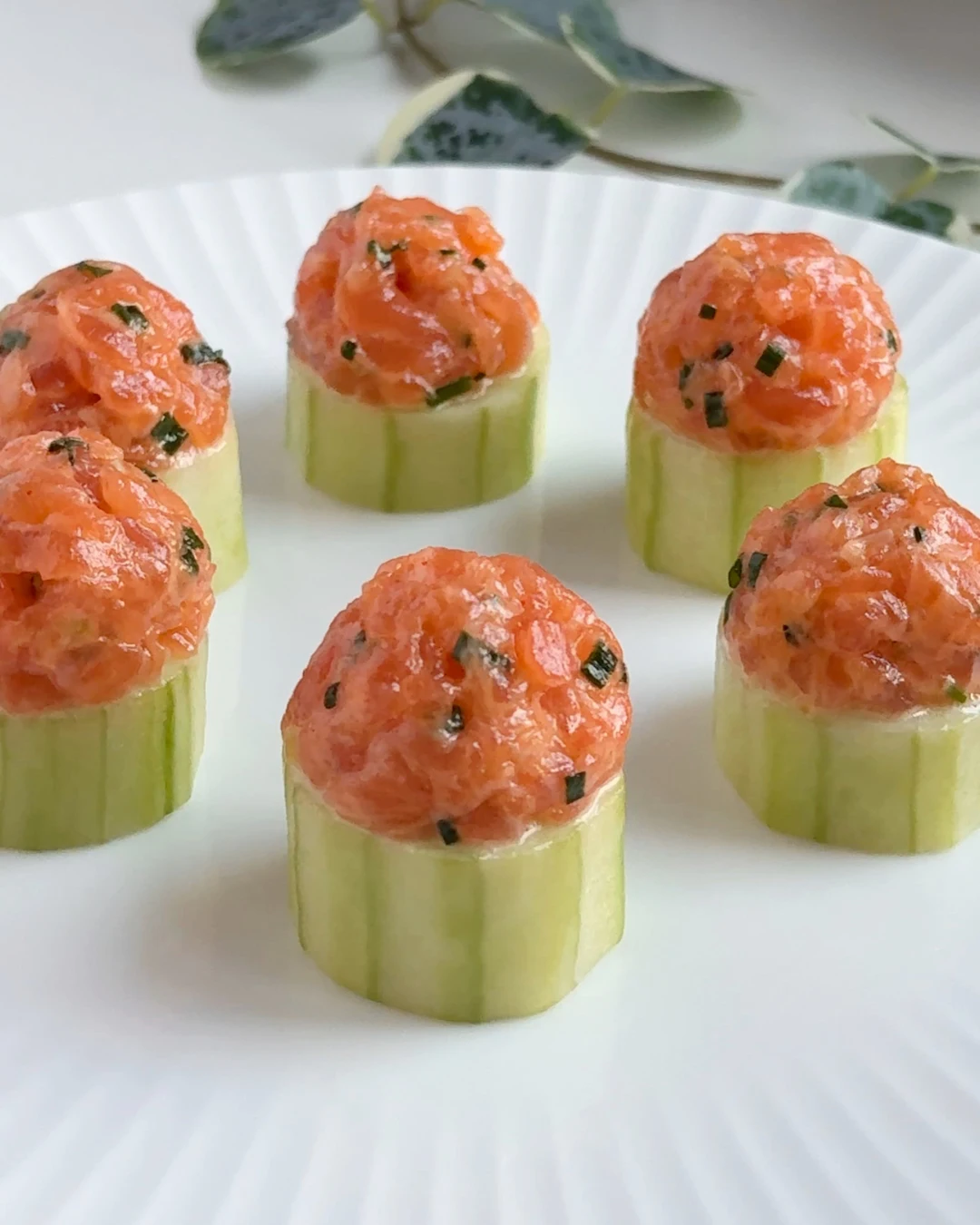 Spicy salmon cucumber cups topped with creamy sriracha salmon, served as bite-sized appetizers on fresh cucumber slices. Recipe by Amy Aversa, Sweet Basil Catering NYC